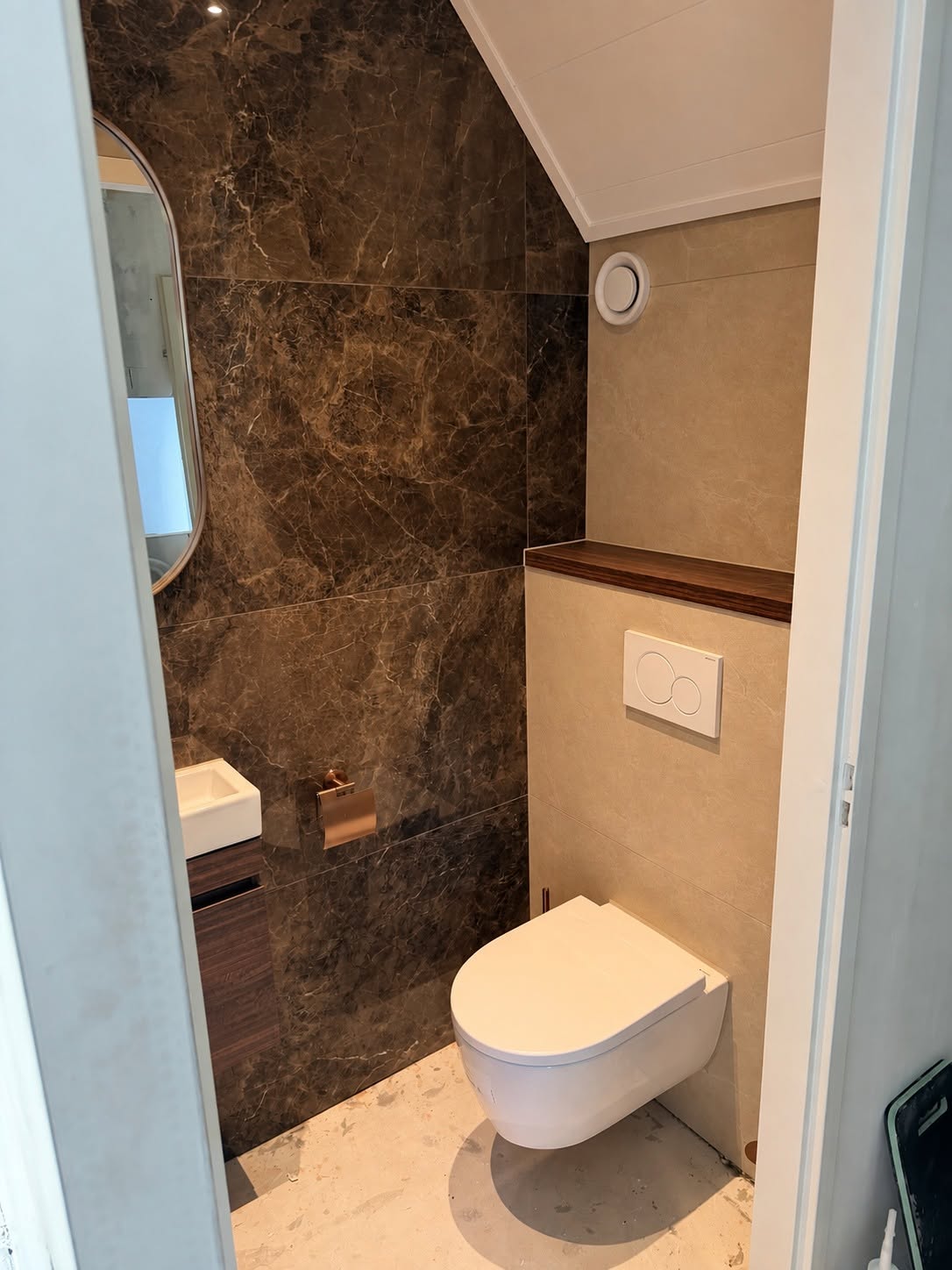Compacte toiletruimte met wandcloset, betegeld inbouwreservoir en donkere accentwand