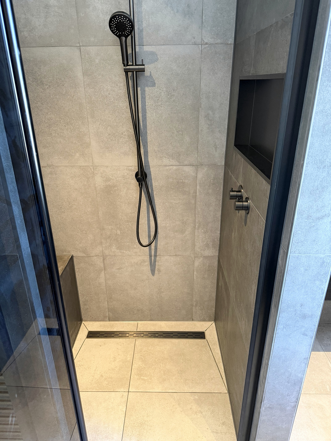 Detail van de inloopdouche met handdouche, nis en lijngoot